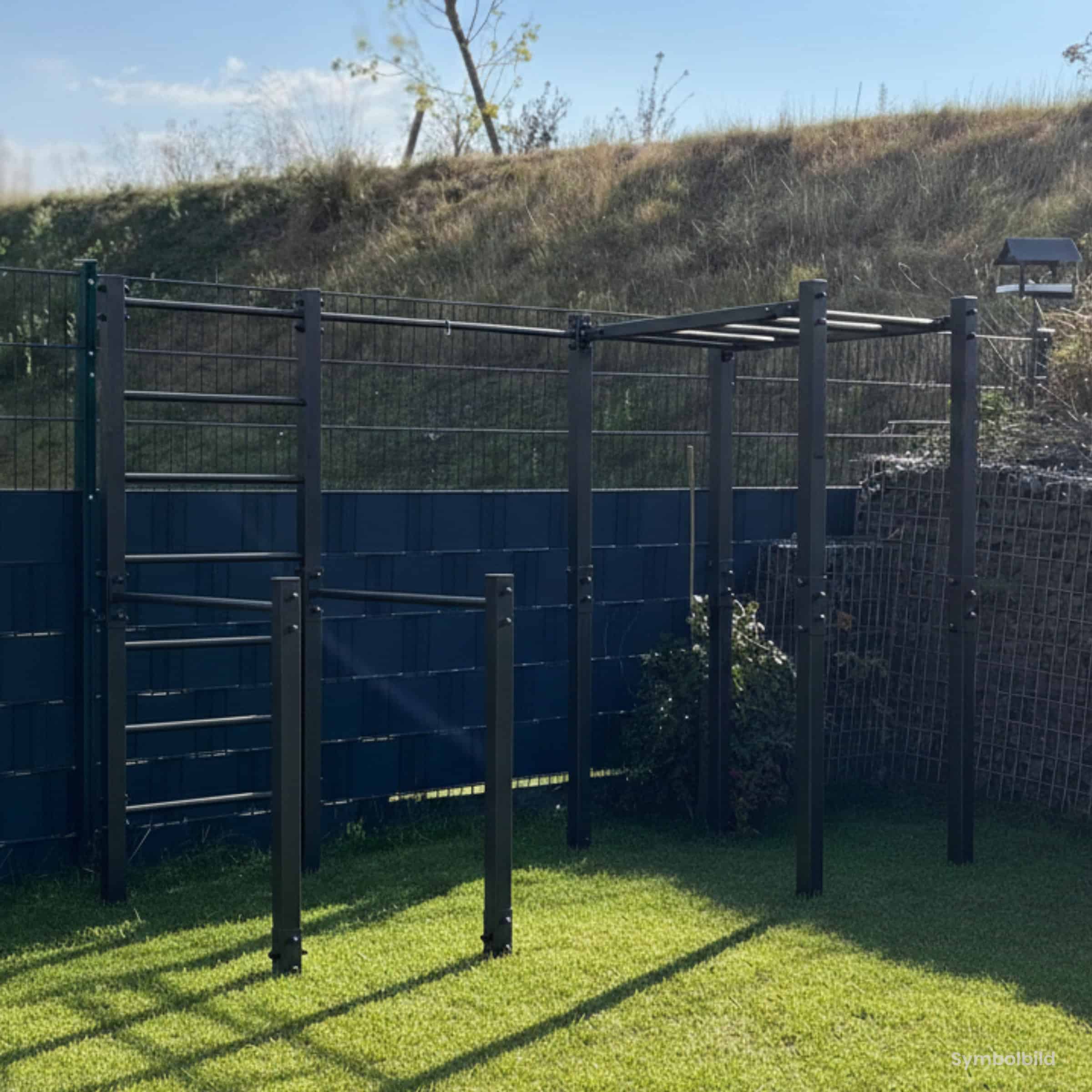 Outdoor-Calisthenics-Station aus Metall mit Sprossenwand, Hangelleiter und Klimmzugstange im Garten vor einem dunklen Sichtschutzzaun