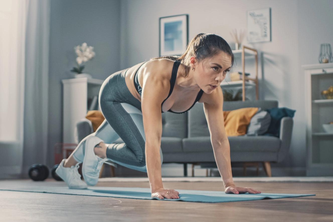 Frau trainiert motiviert zu Hause nach dem Urlaub – Fitness Wiedereinstieg mit Bodyweight Übungen