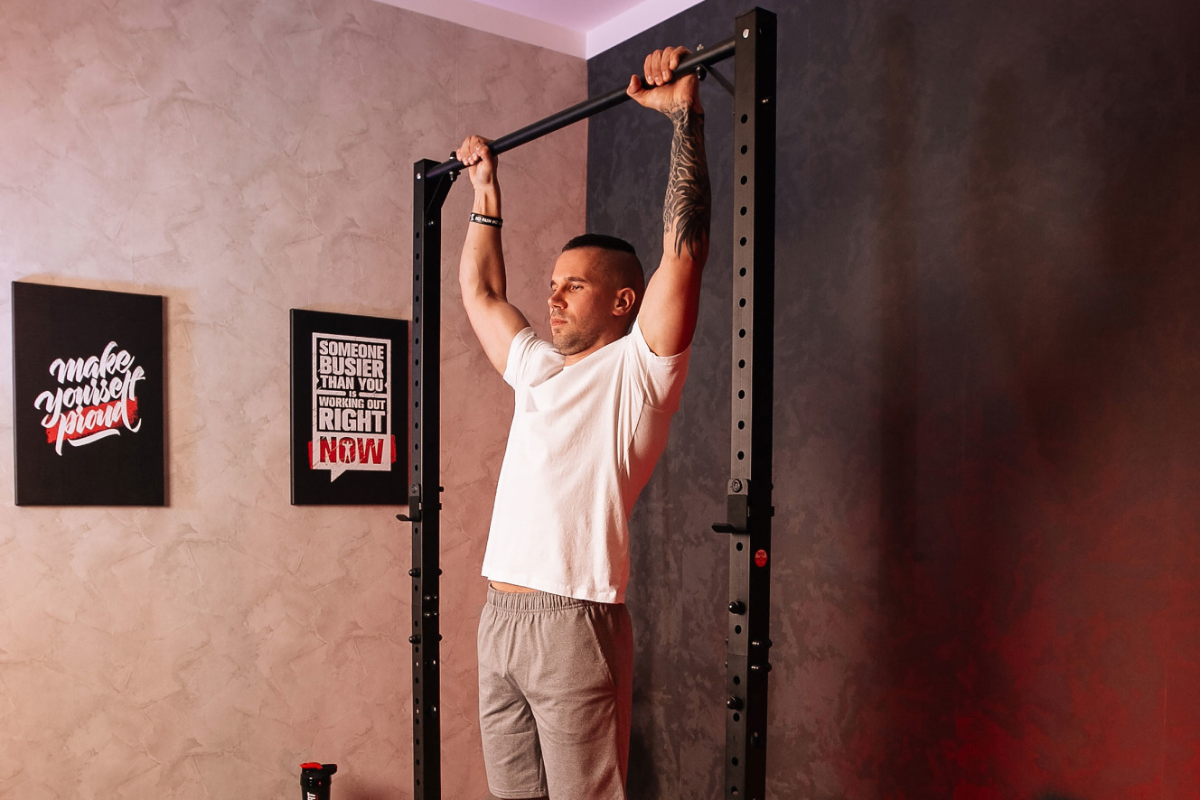 Mann macht Klimmzüge an einer Power Tower Pull-Up Station in einem modern eingerichteten Home-Gym.