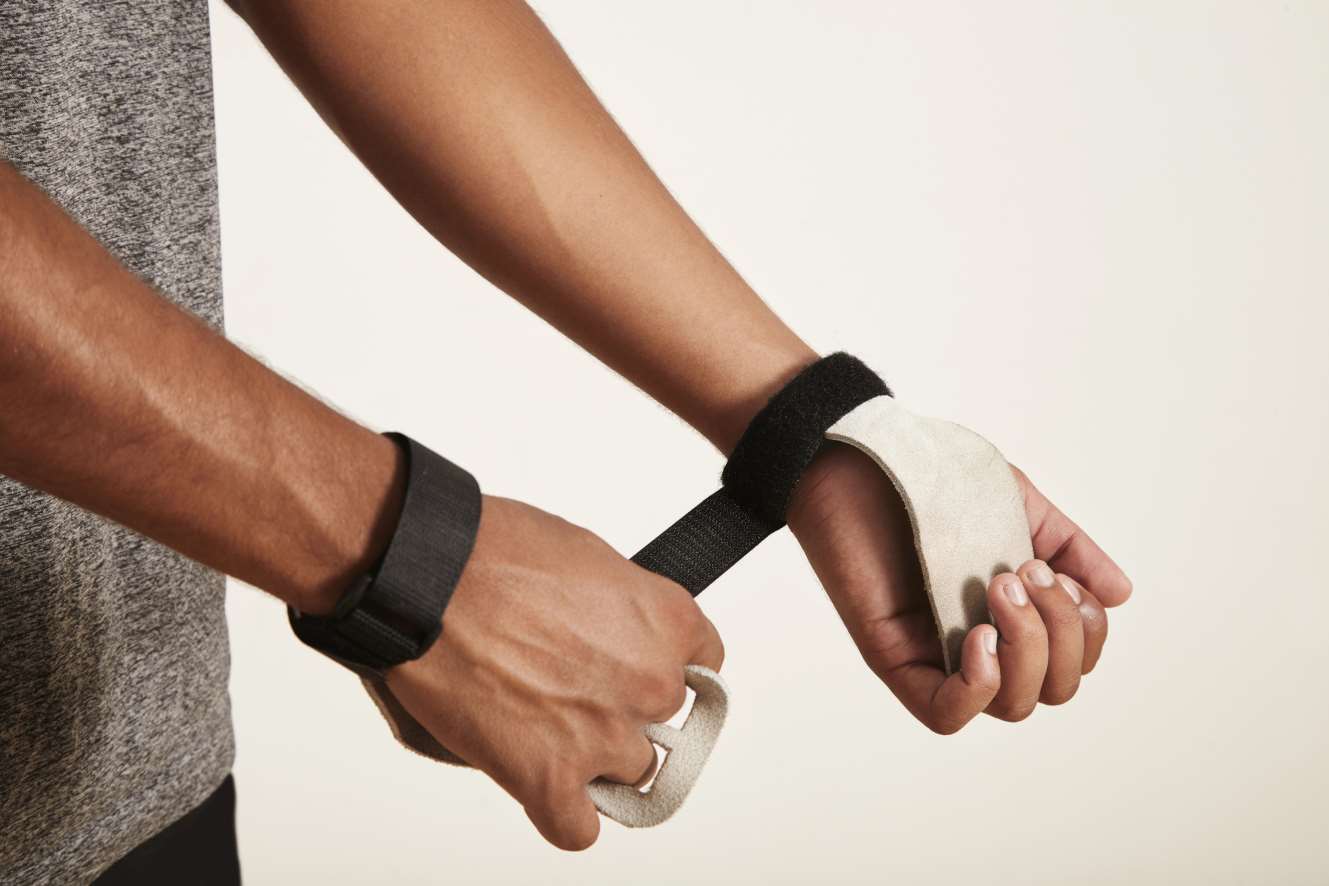 Person legt Griffkraftunterstützung mit Handgelenksband für Krafttraining an